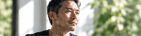 窓辺で外を見つめる中年の男性